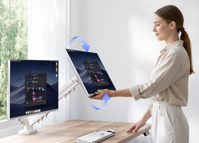 Persona girando a vertical un monitor en el brazo F5 junto a un escritorio de pie